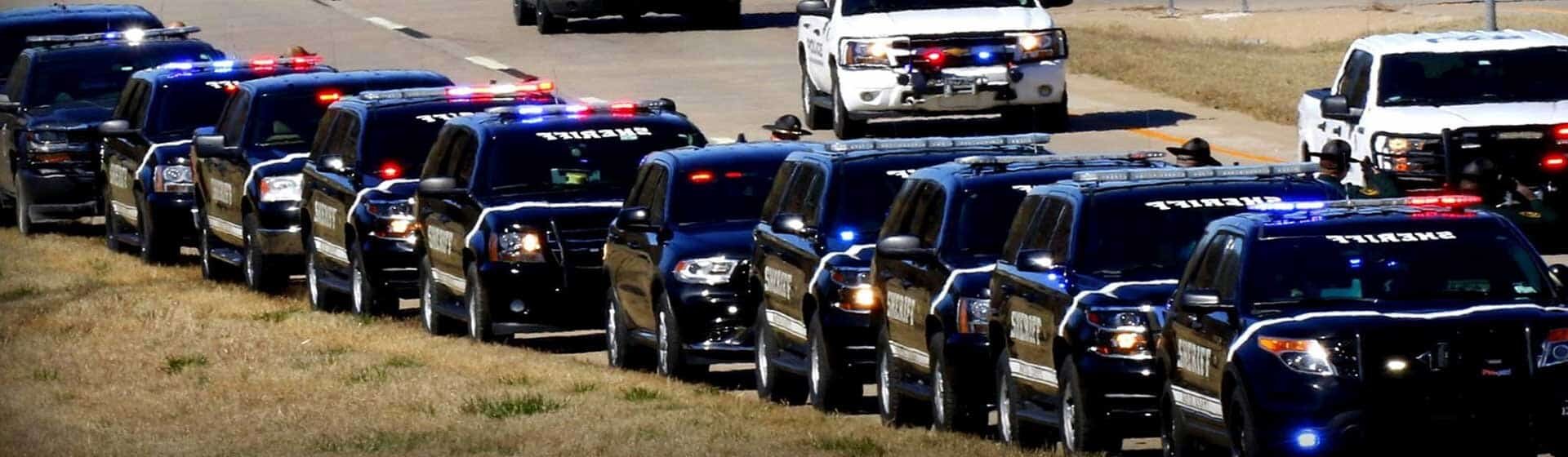 A squad of police vehicles driving on the road.